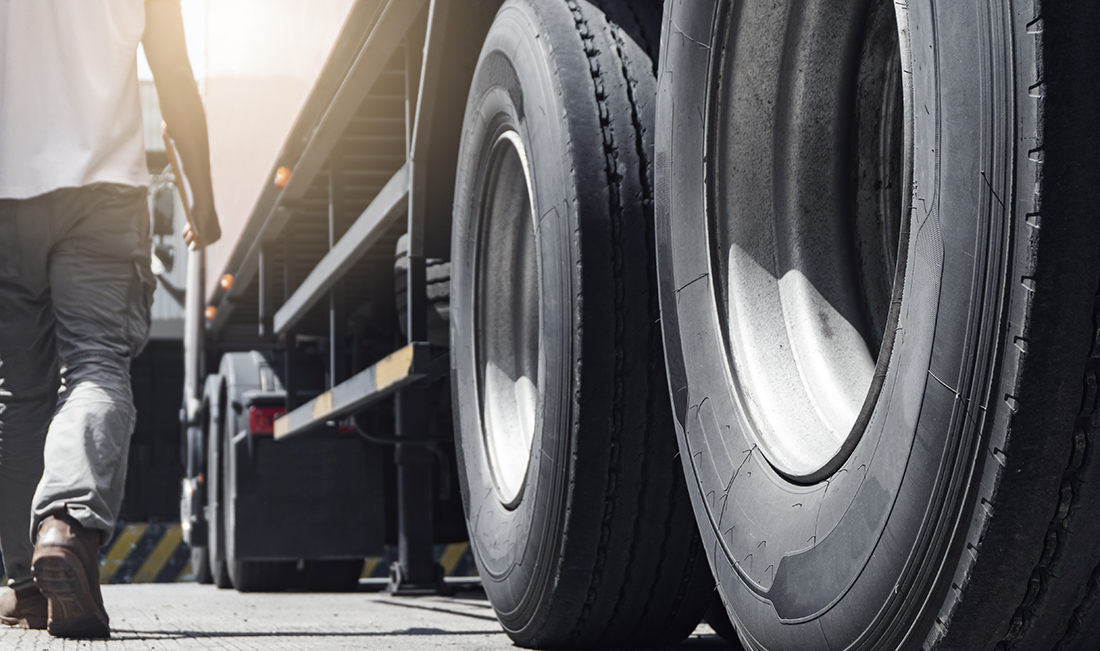 Closeup a truck wheels and a truck driver holding clipboard insp